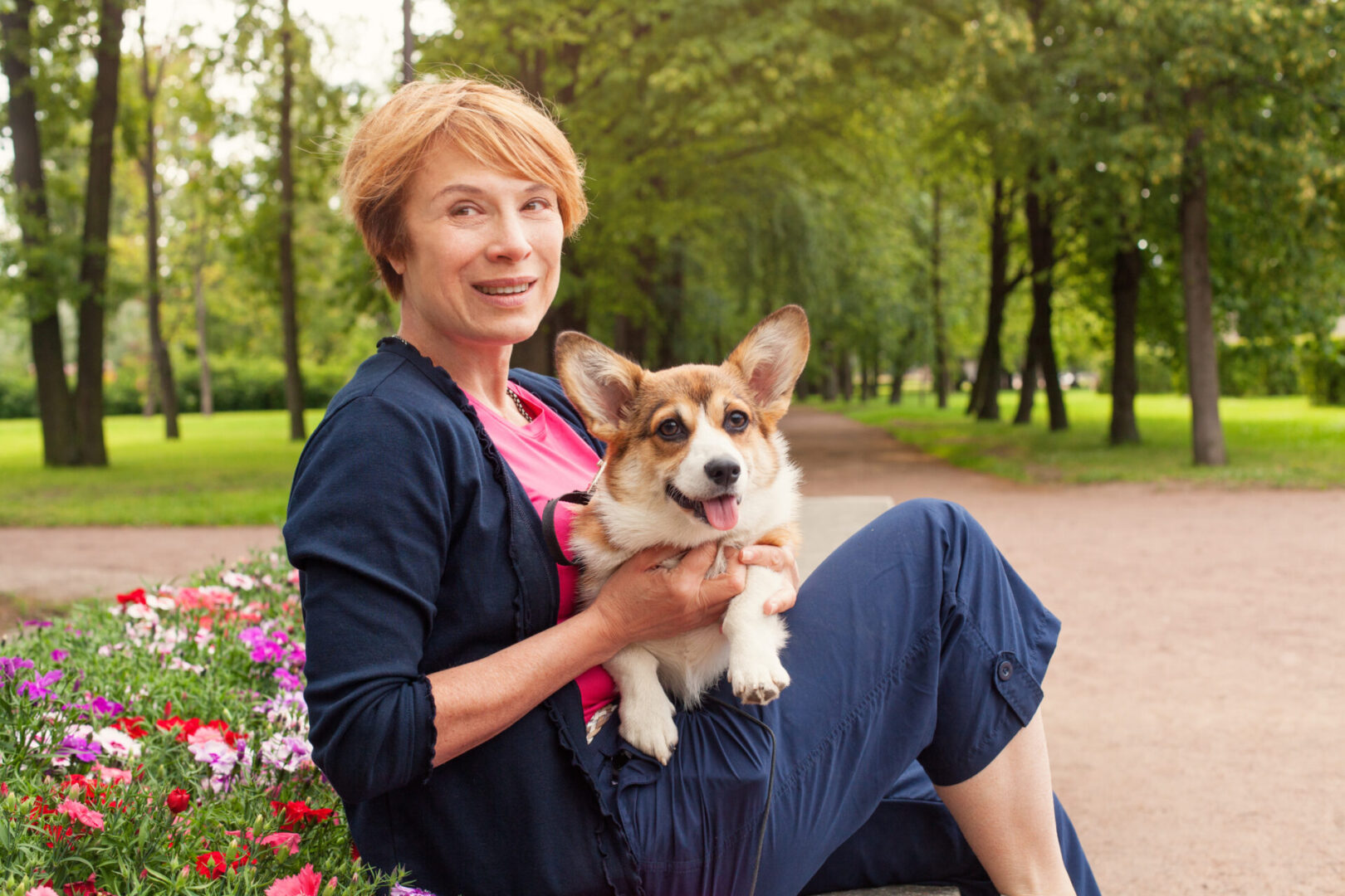 Senior woman with her cute white dog outdoor in summer park